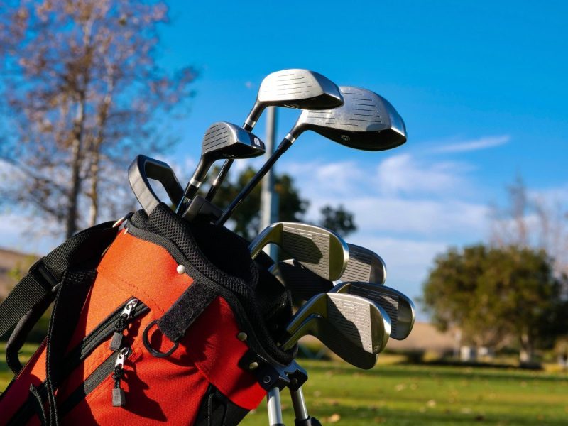 A golf bag with clubs in it out on the golf course.