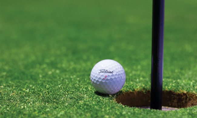 a golf ball on course on edge of hole