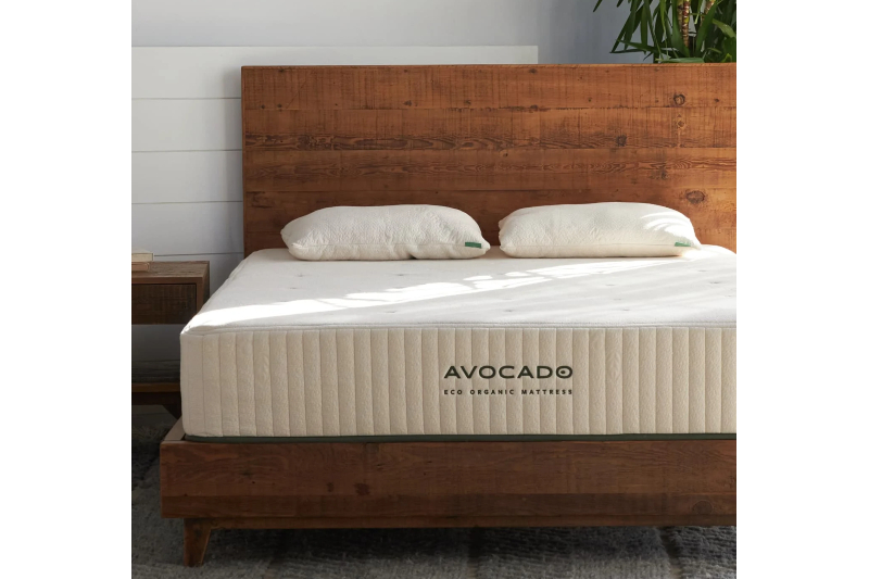 An Avocado Green mattress on a wooden bed frame in a bedroom.