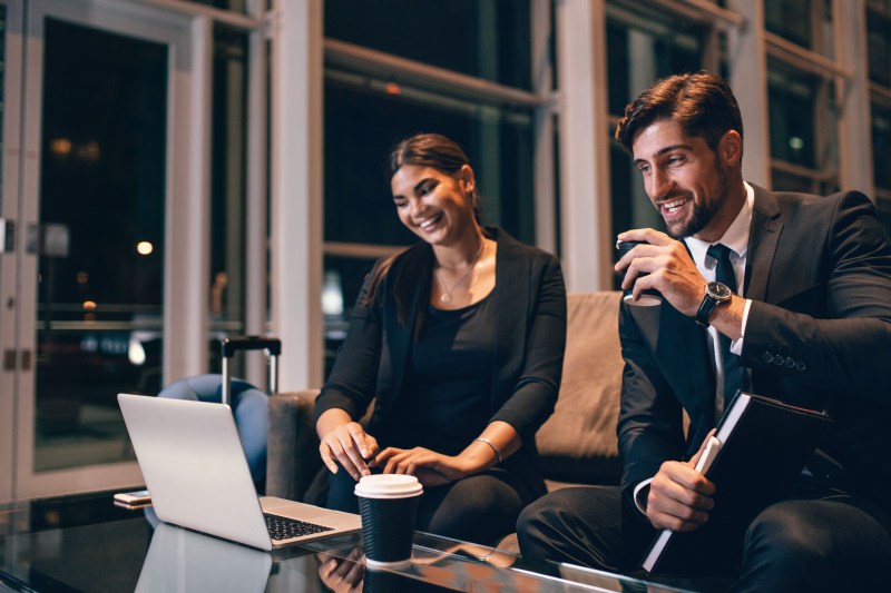 Businessman and business woman looking at laptop in airport lounge