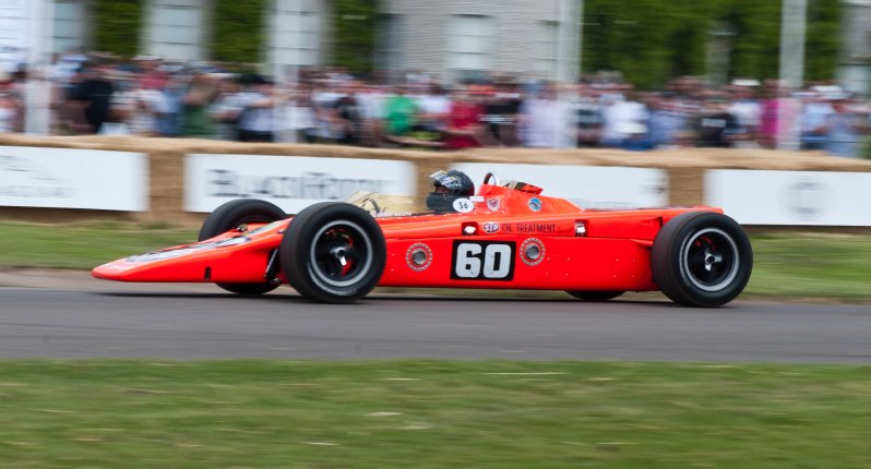 A man in a race car driving on a track.