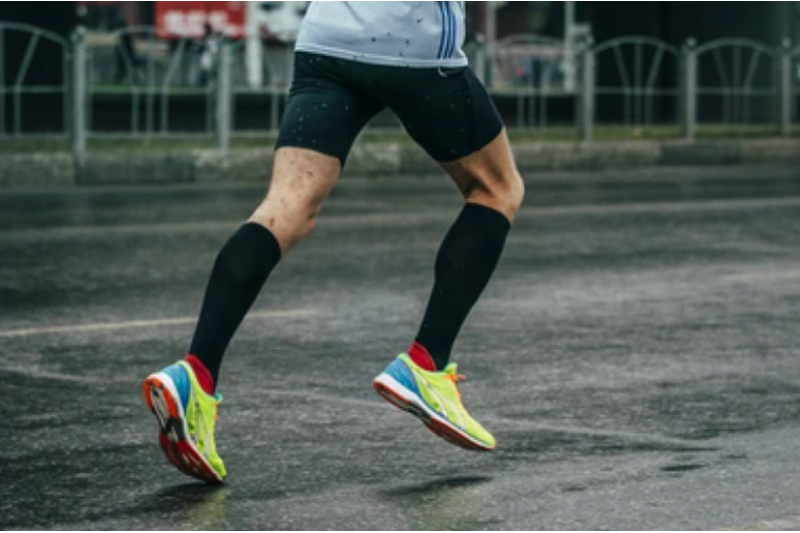 Runner wearing black compression socks while running on pavement