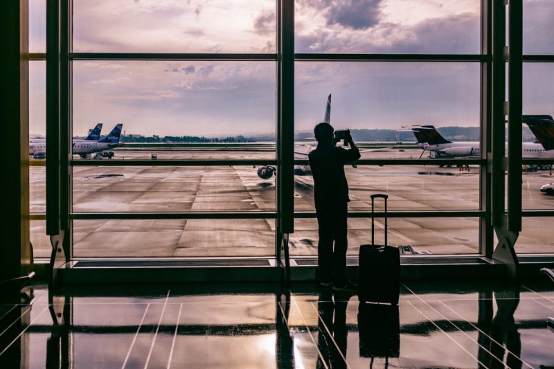 An airport passenger waiting for a flight looking out the window.