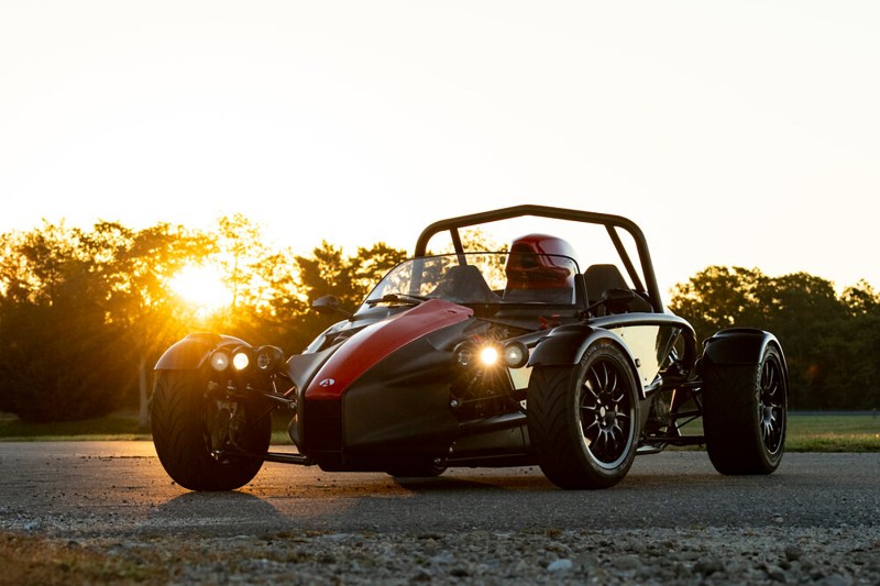 Ariel Atom 4 open-cockpit racecar, parked with sunset in the background.