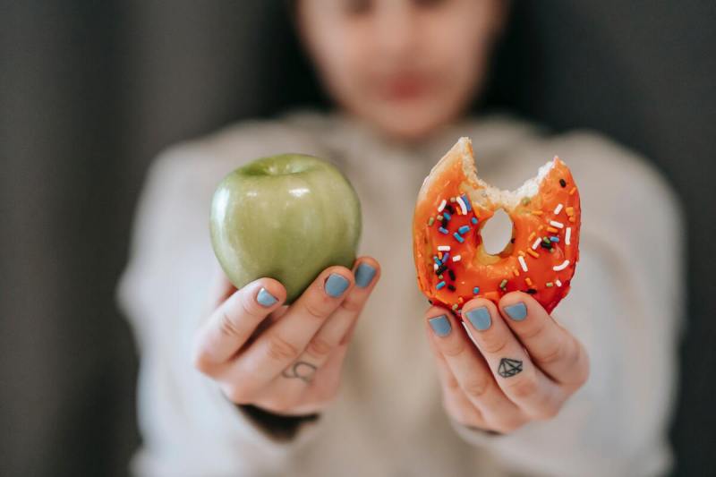 Person holding up an apple and a donut