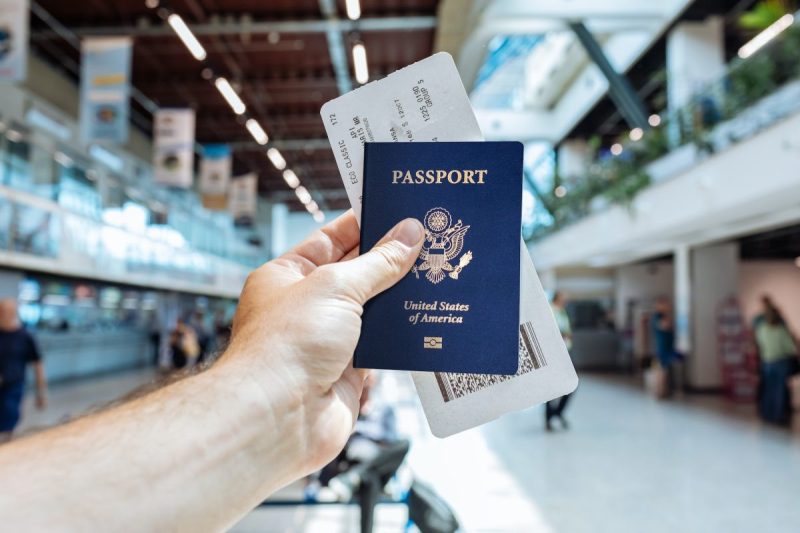 A person holding up their passport in an airport.