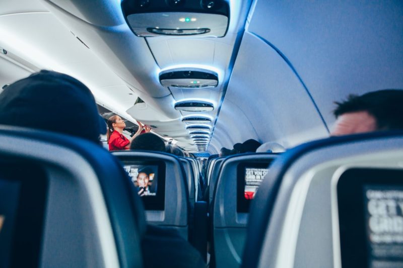 A flight attendant checking on the inside of a cabin on an airplane.