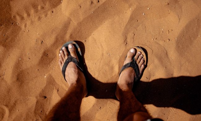 foot in sand flip flops
