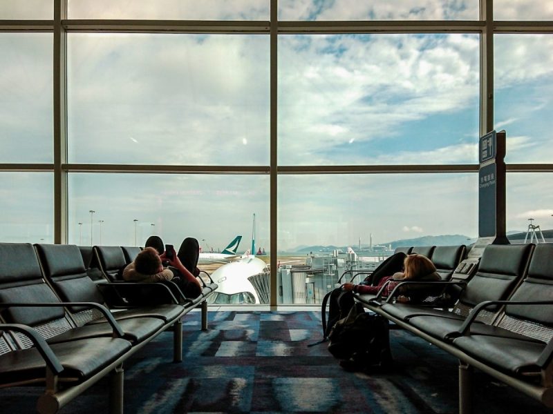 Passengers waiting at the airport, killing time o their phones.