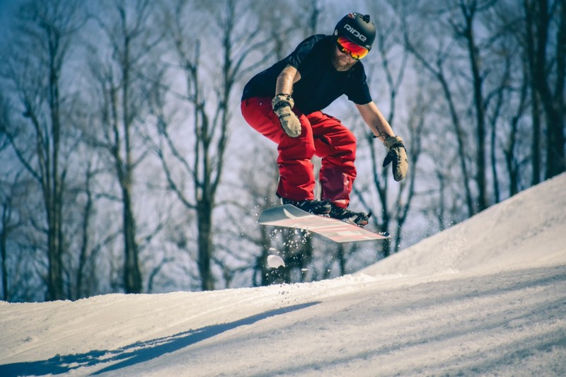 A man in a T-shirt snowboards in spring