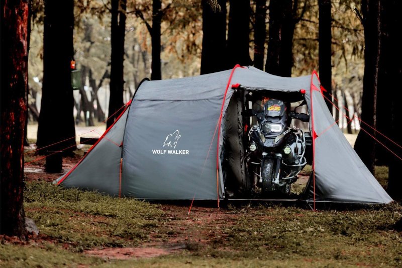 Motorcycle parked inside the Wolf Walker Motorcycle Tent among a stand of trees.