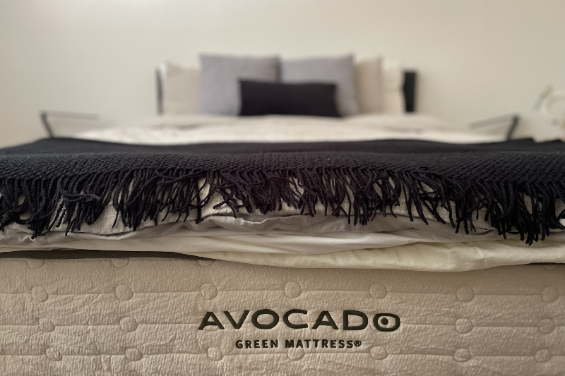 A made bed showing off the Avocado mattress logo.