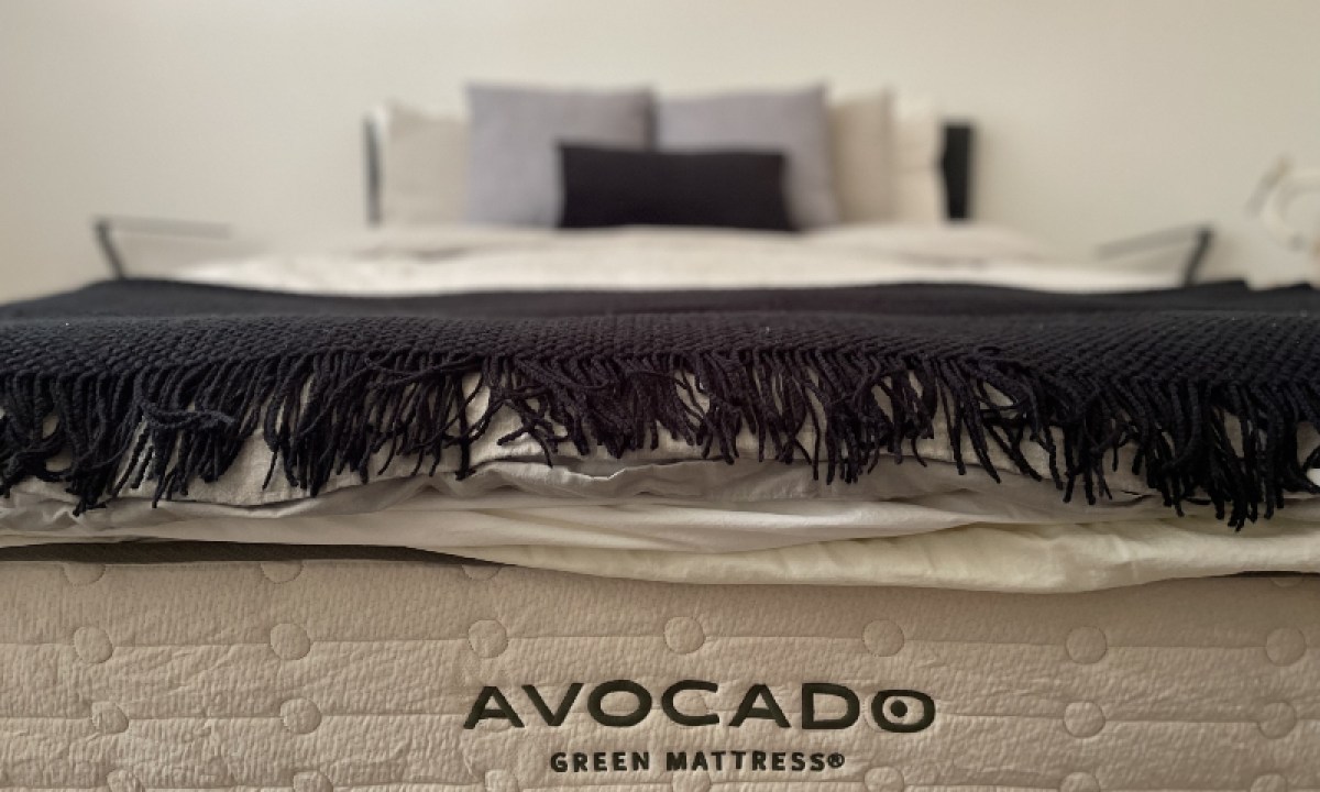 A made bed showing off the Avocado mattress logo.