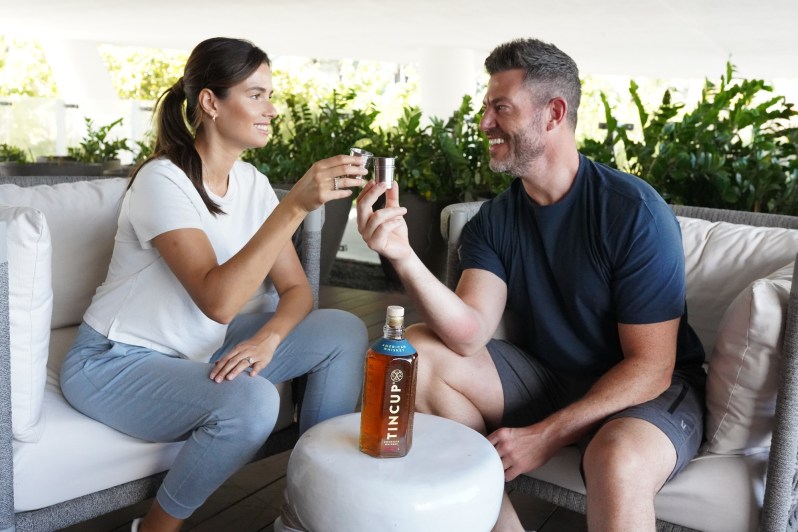 "The Bachelor" host Jesse Palmer at home with his spouse Emely and a bottle of TINCUP whiskey.