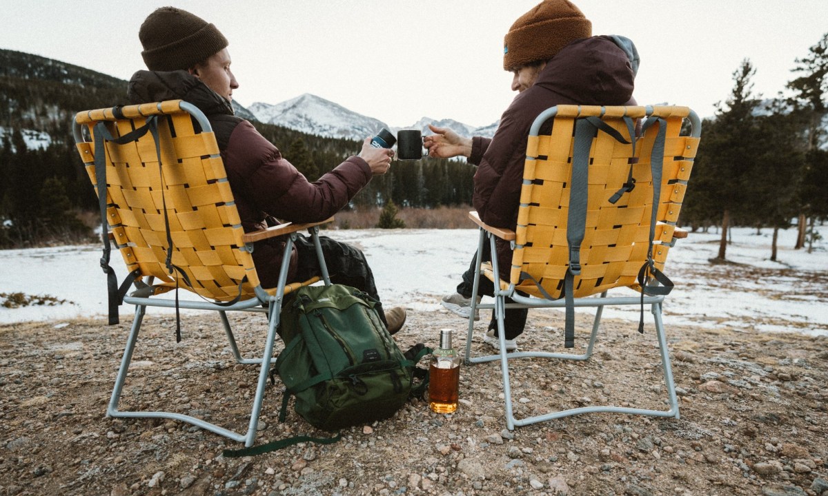A couple of people enjoy a bottle of TINCUP whiskey on a snowy mountain day.