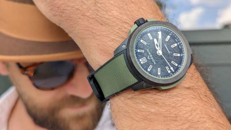 Man wearing Norqain watch and adjusting his hat