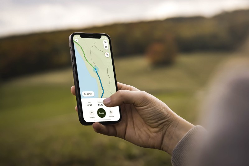 A person holding a phone with the AllTrails maps open.