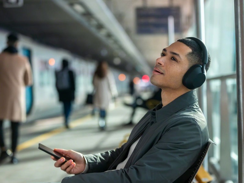 Listening to music in an airport with the Sony WH-1000XM5 wireless headphones.