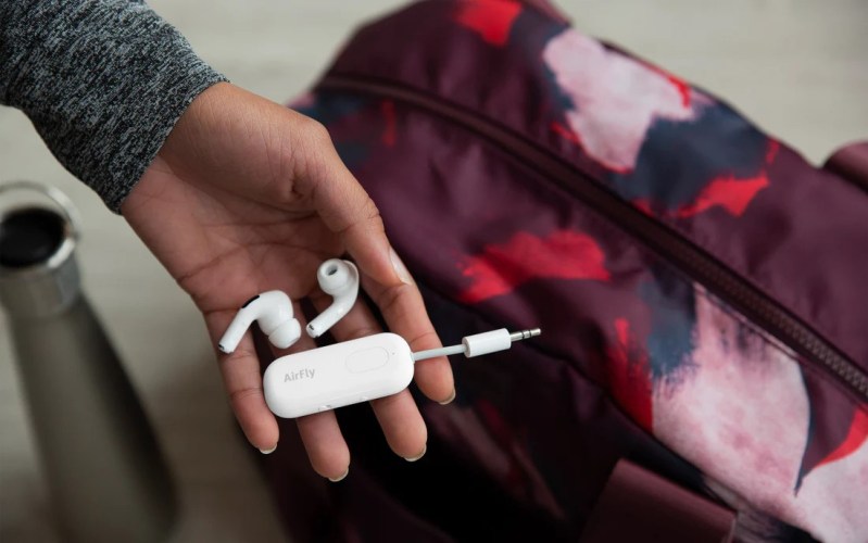 A person packing airpods and an AirFly device.