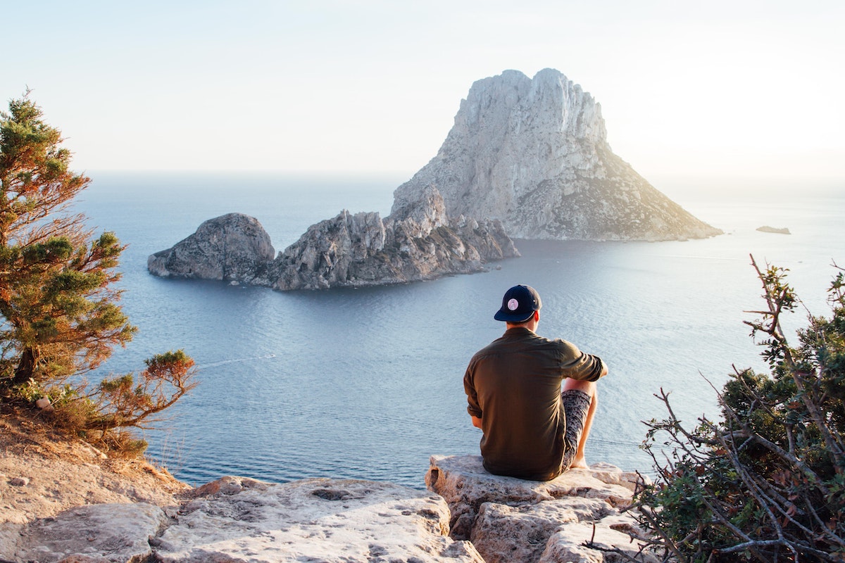 the backshot of a man overlooking a beach