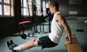 A man doing a tricep bench dip white shirt