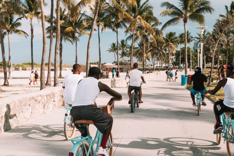 People riding bikes and walking along Miami Beach.