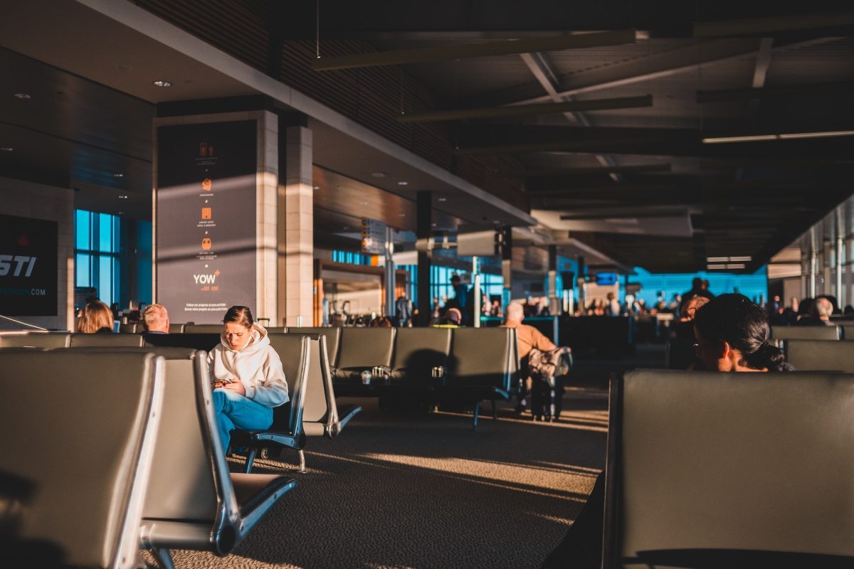 A view of a crowded airport with people sitting in the seats.