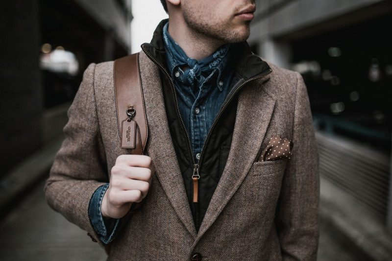 A man dressed stylishly holding onto a shoulder bag