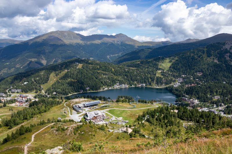 A ski resort in the summer with a lake and resort buildings.