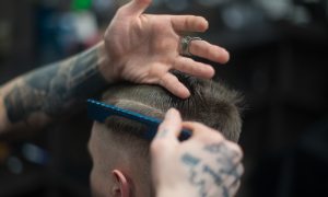 A man getting a haircut from tattooed barber