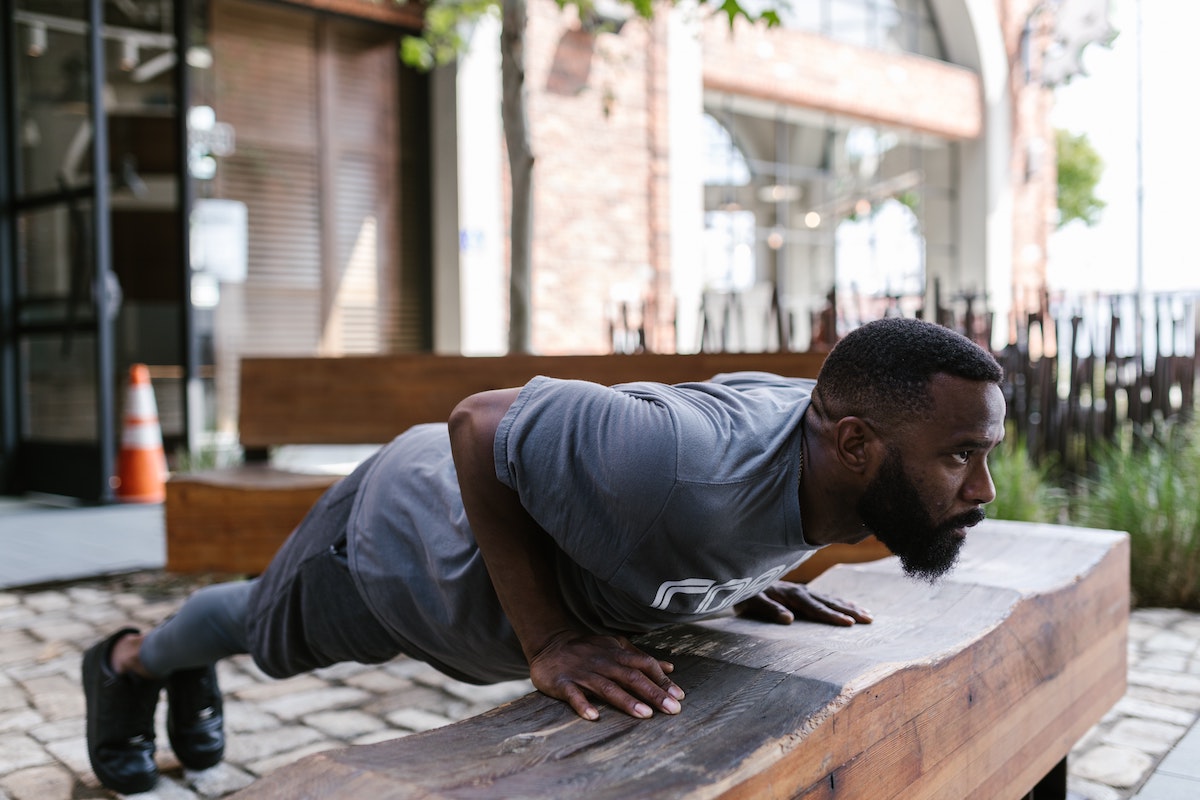 a man using a slab of wood to do pushups outside