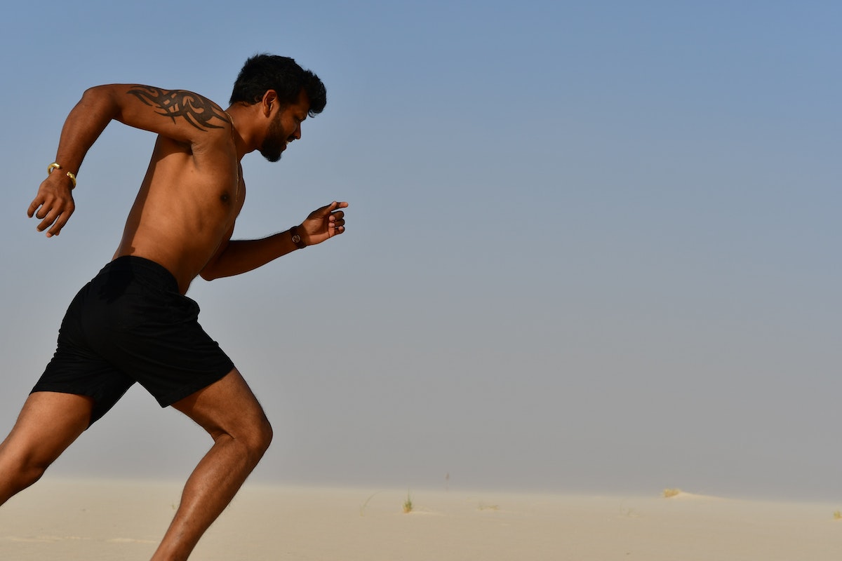 a man running on the beach without a shirt on