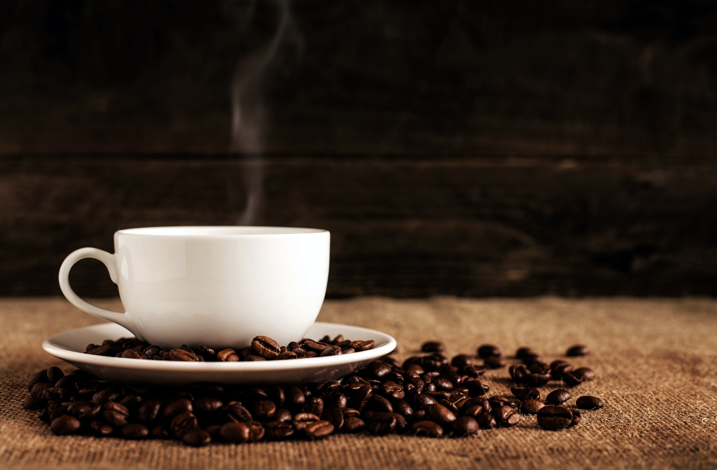 Cup of coffee with beans on table