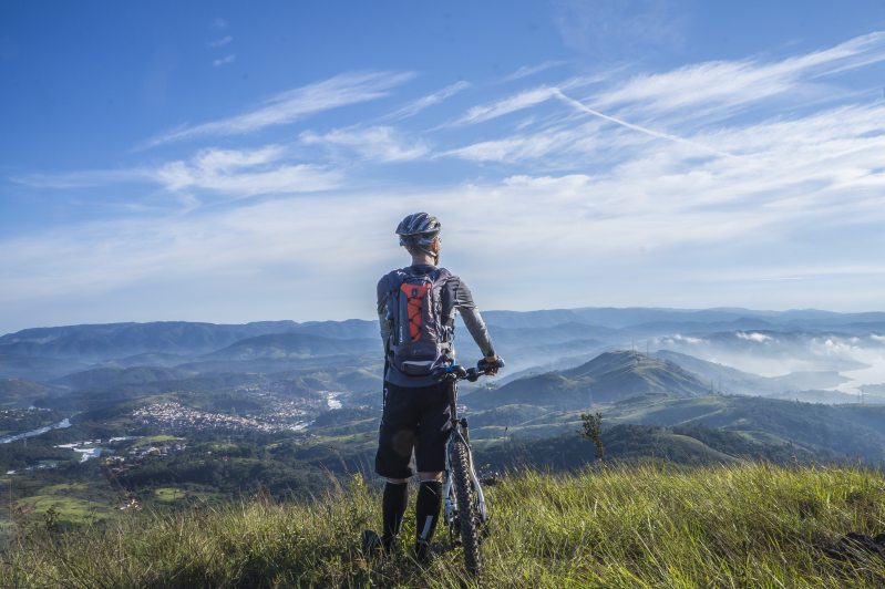 mountain biker stands at top of a mountain