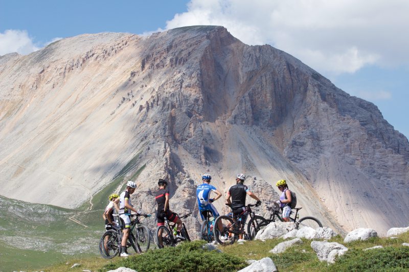 A group of mountain bikers with a large mountain behind them