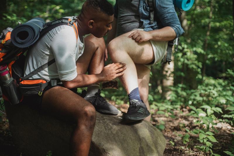 A man searches another man for ticks on the trail