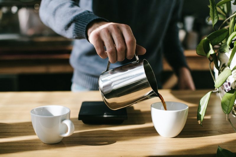 man in blue sweater making cup of coffee