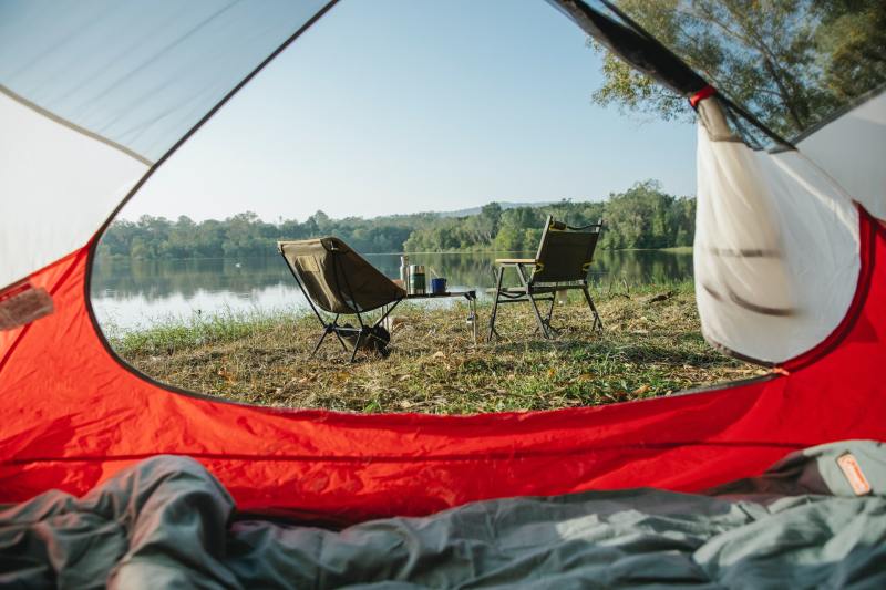 The view from an MSR tent looking out over camping chairs and a lake.