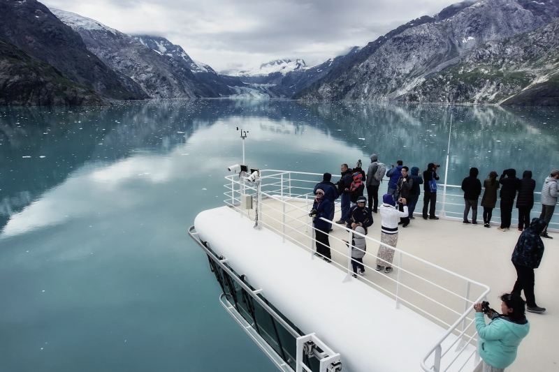 Group of travelers gathered on the bow of a cruise ship in Alaska's Glacier Bay National Park.