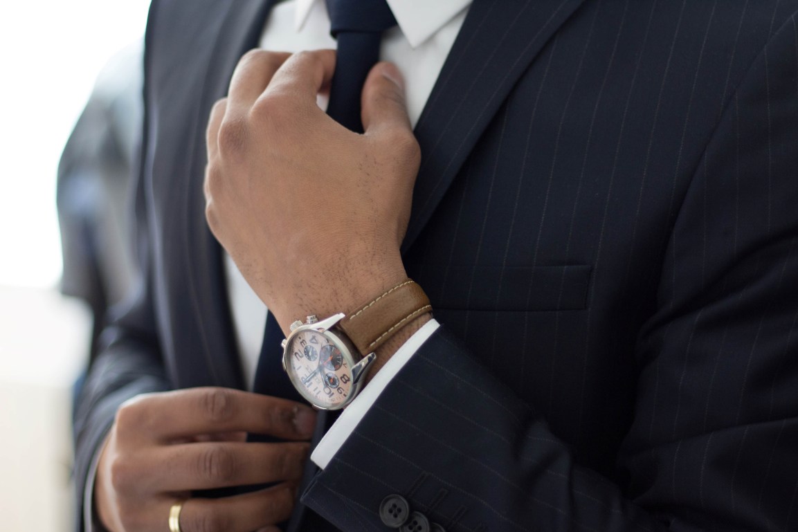 Man adjusting his tie wearing a watch
