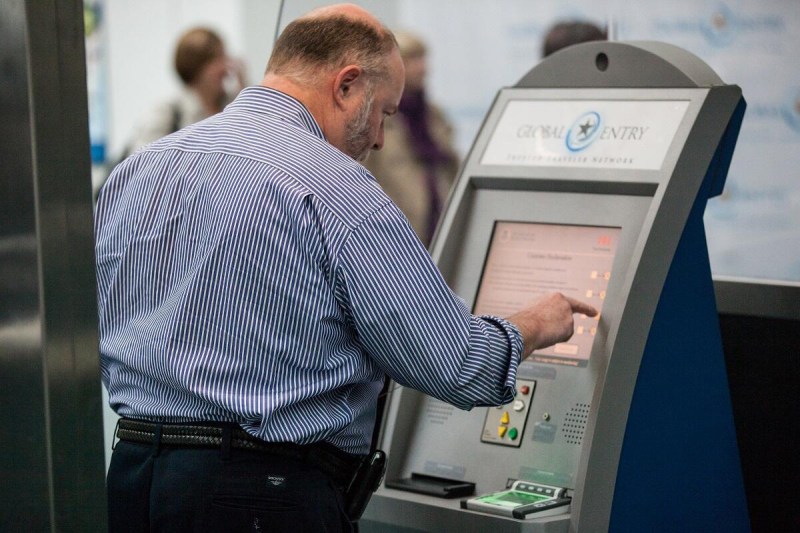 Air traveler entering information at a Global Entry airport kiosk.