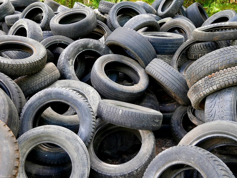 A heap of used car tires in different stages of use.