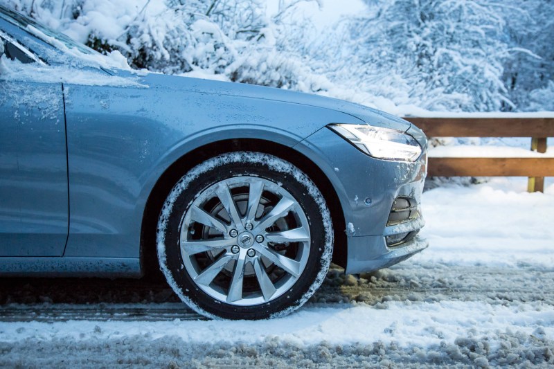 Un coche y sus neumáticos conduciendo sobre la nieve.