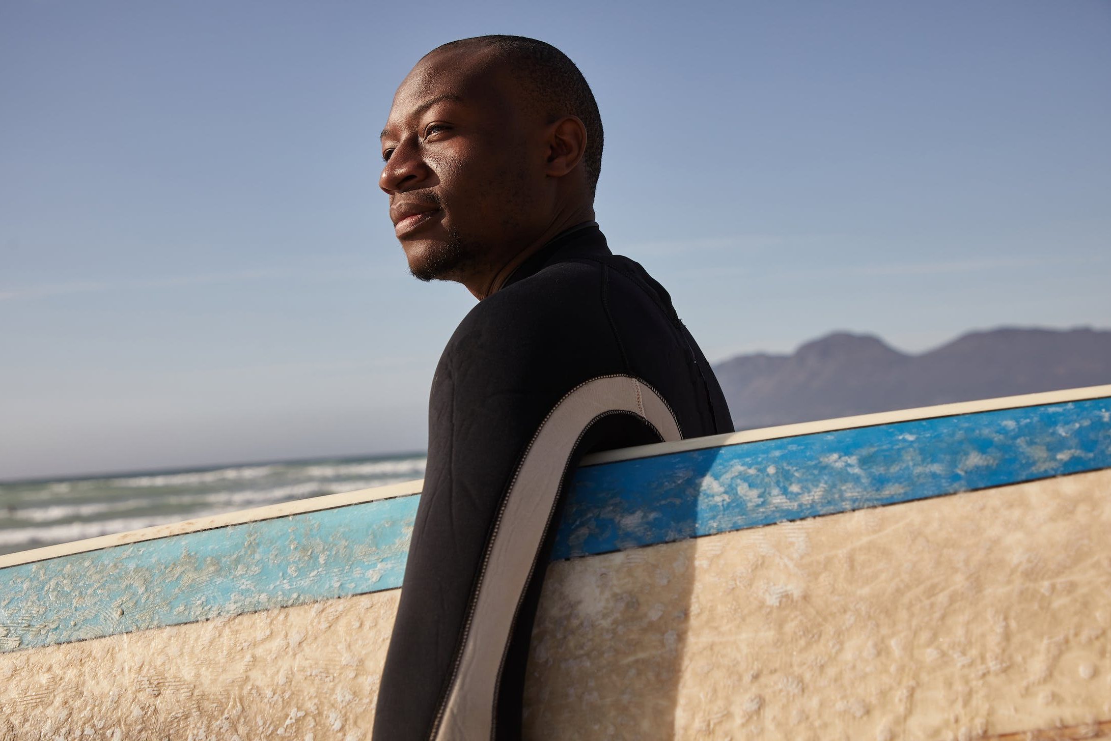 Bald man holding surfboard in the sun