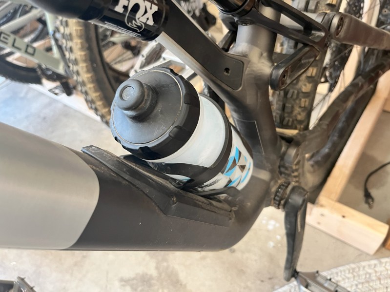 A water bottle in a water bottle cage on a mountain bike