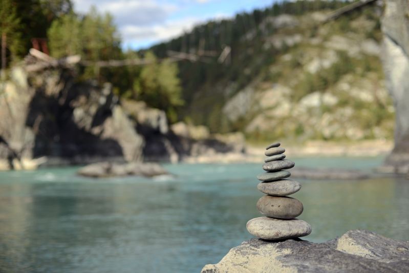 A rock cairn near mountains and water.