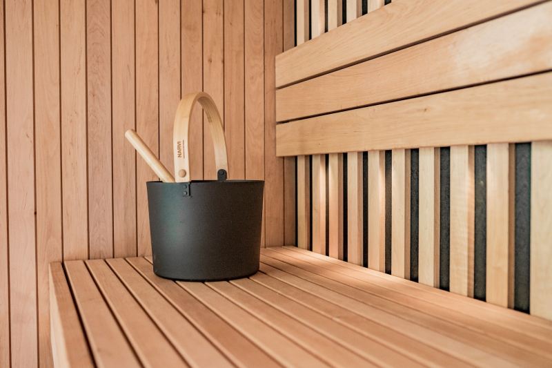Black sauna bucket on top of a sauna bench.