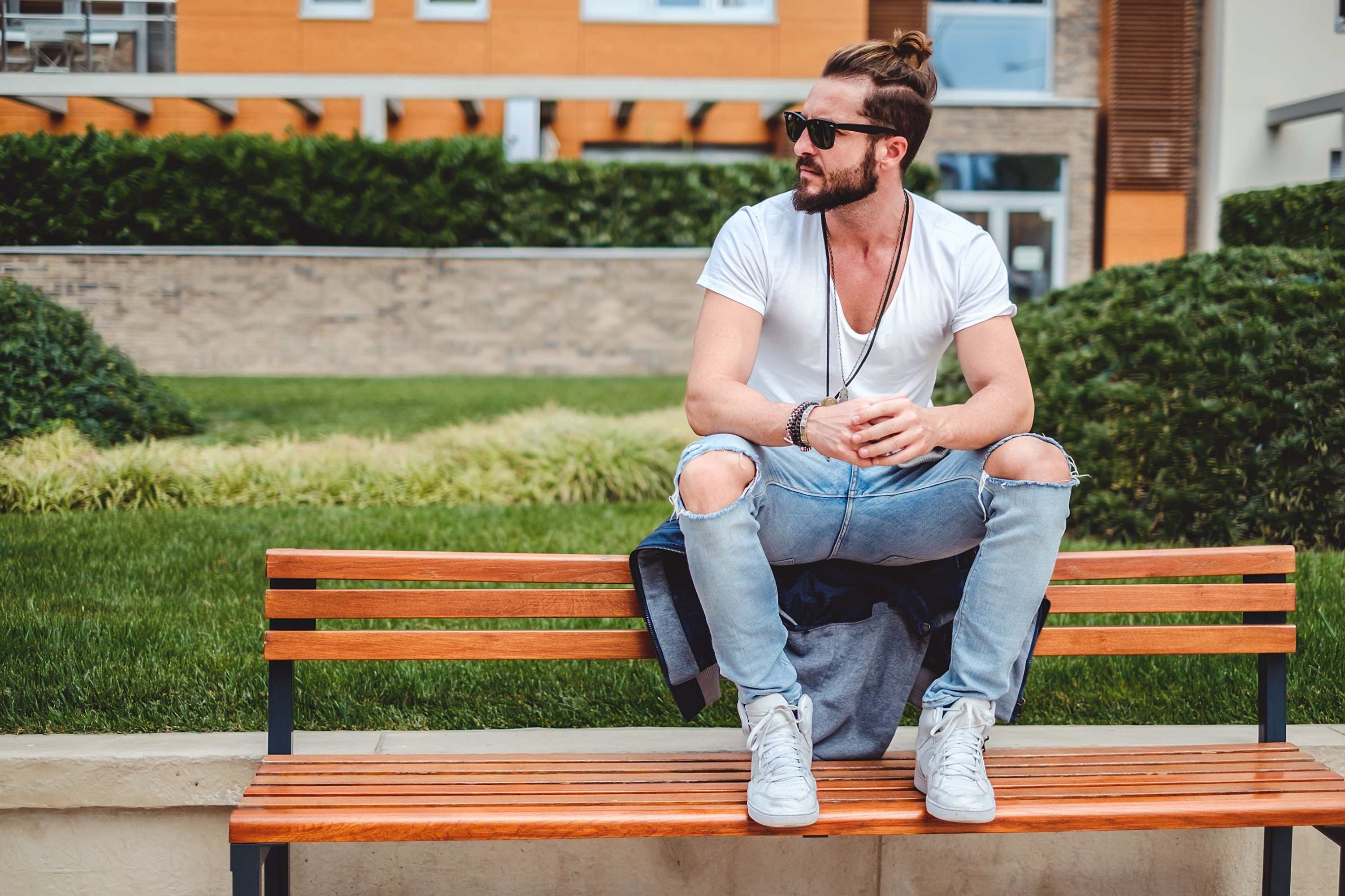 Man sitting on bench with ripped jeans