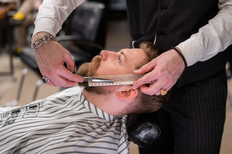 A man getting his beard trimmed at the barber