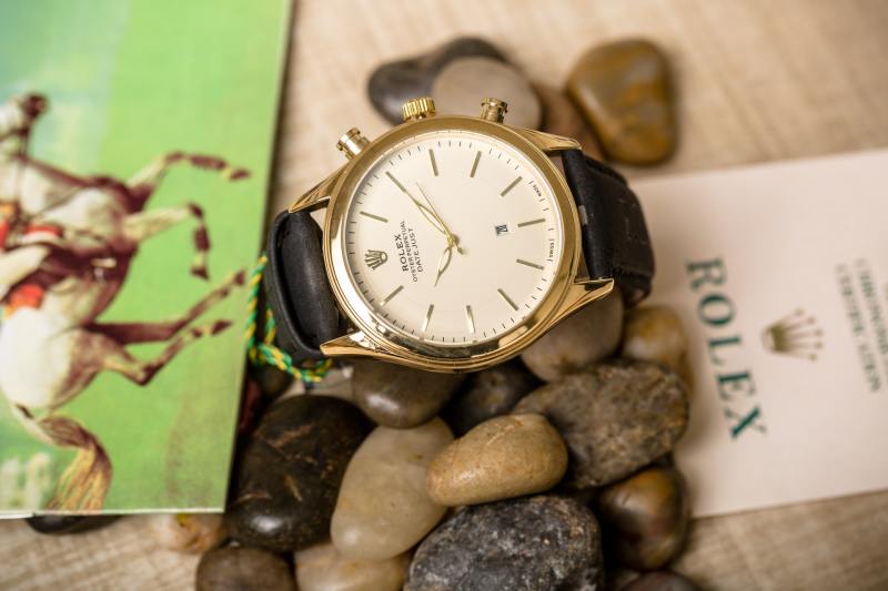 A vintage Rolex Oysterdate sitting on some pebbles.